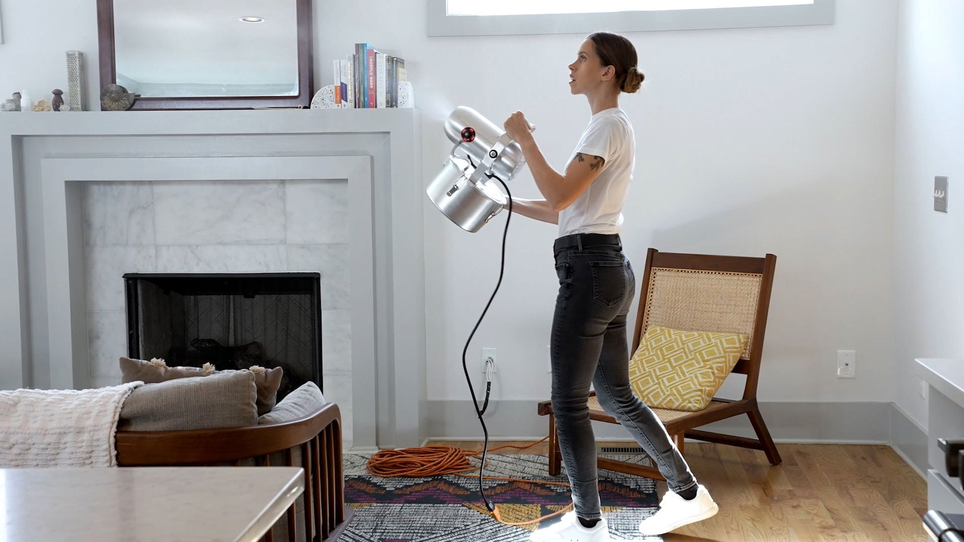 A woman fogging a bright living room with a SuperStratum fogger.